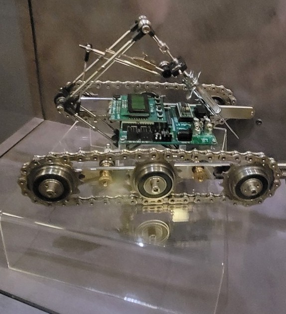 Figure 3 — A clean three-quarter reference view of the whole object: the low
tracked base, the central control deck, and the forward truss carrying the glass
syringe.