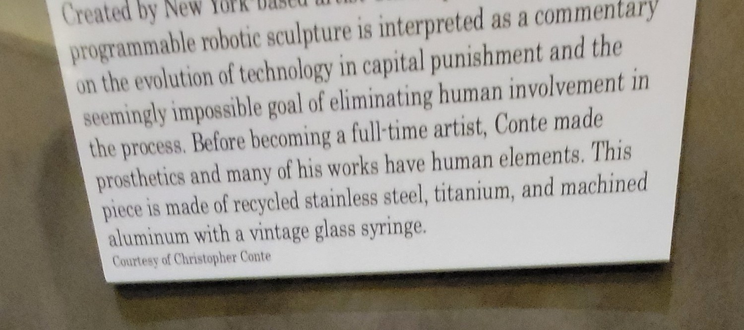 Figure 2 — The museum's interpretive placard, which fixes the work's reading as
a commentary on automating capital punishment and "the seemingly impossible goal
of eliminating human involvement in …
