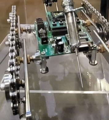 Figure 3 — The actual deck as a catalogue of the method: the Parallax board, the
glass syringe body, brass fittings, machined sprockets, and small springs combined
into a single assembled object.
