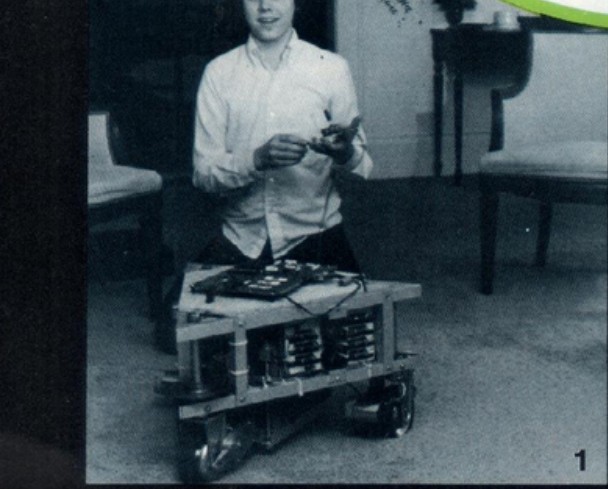 Figure 2 — A photograph of a young Tod Loofbourrow with the rolling chassis,
showing the aluminum frame structure, motorized wheel assemblies, and the plywood
board carrying the KIM-1. Source: Inte…