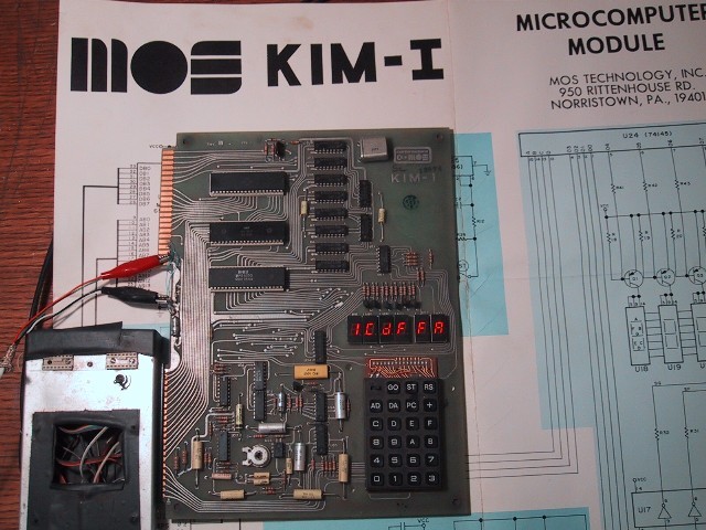 Figure 2 — The KIM-1 board powered and in operation. The six-digit LED display
shows a hexadecimal value in red. A small external power supply is connected via
alligator leads. The MOS Technology "…