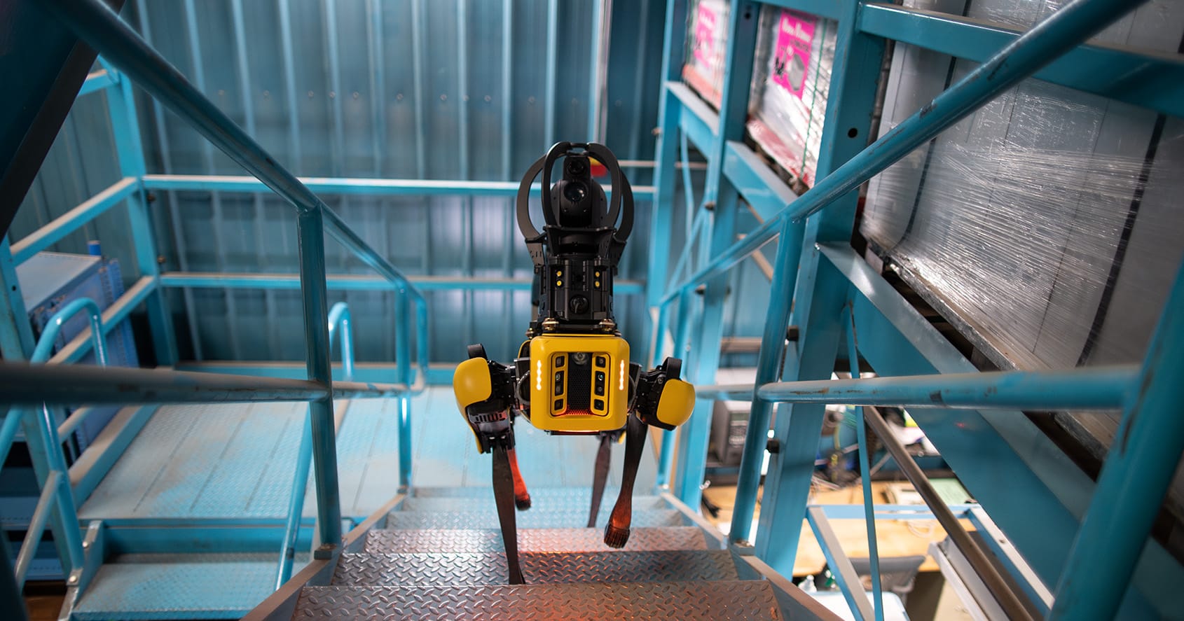 Figure 2 — Boston Dynamics Spot navigating stairs with its safety-light array active. Spot's 90-minute runtime and 14 kg payload set the performance baseline for serious commercial quadruped deployment.